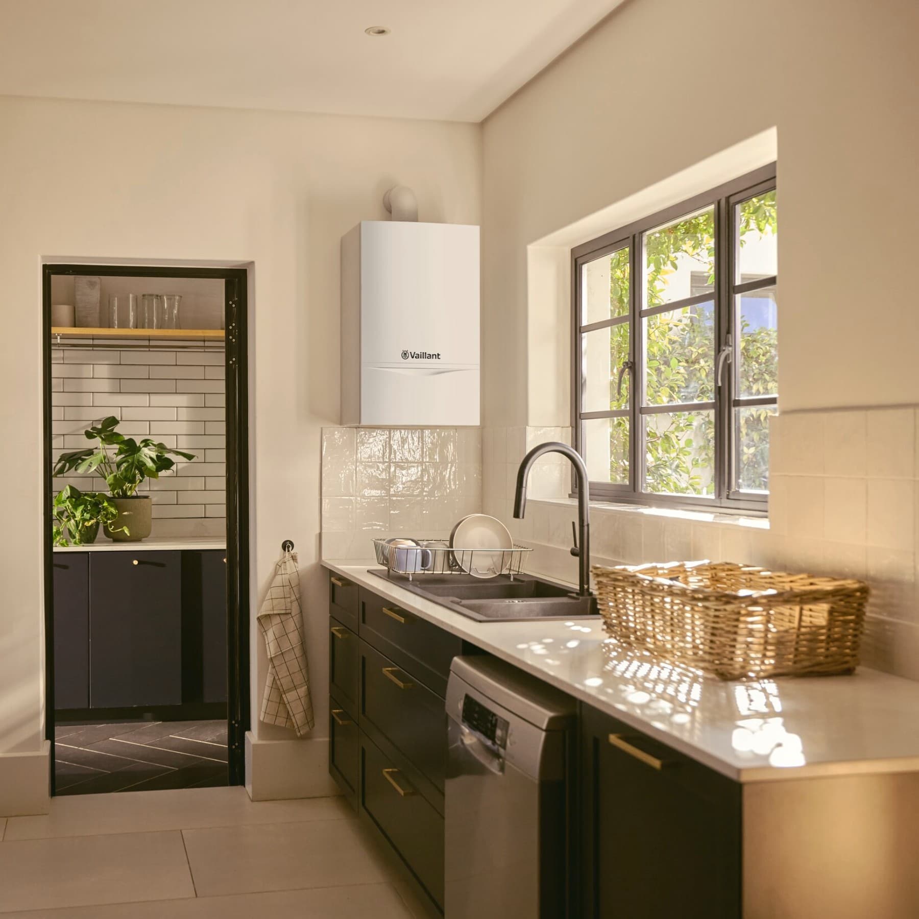 Das Vaillant Heizwertgerät atmoTEC plushängt über einer Spüle in der Ecke einer Küche neben dem Türrahmen.