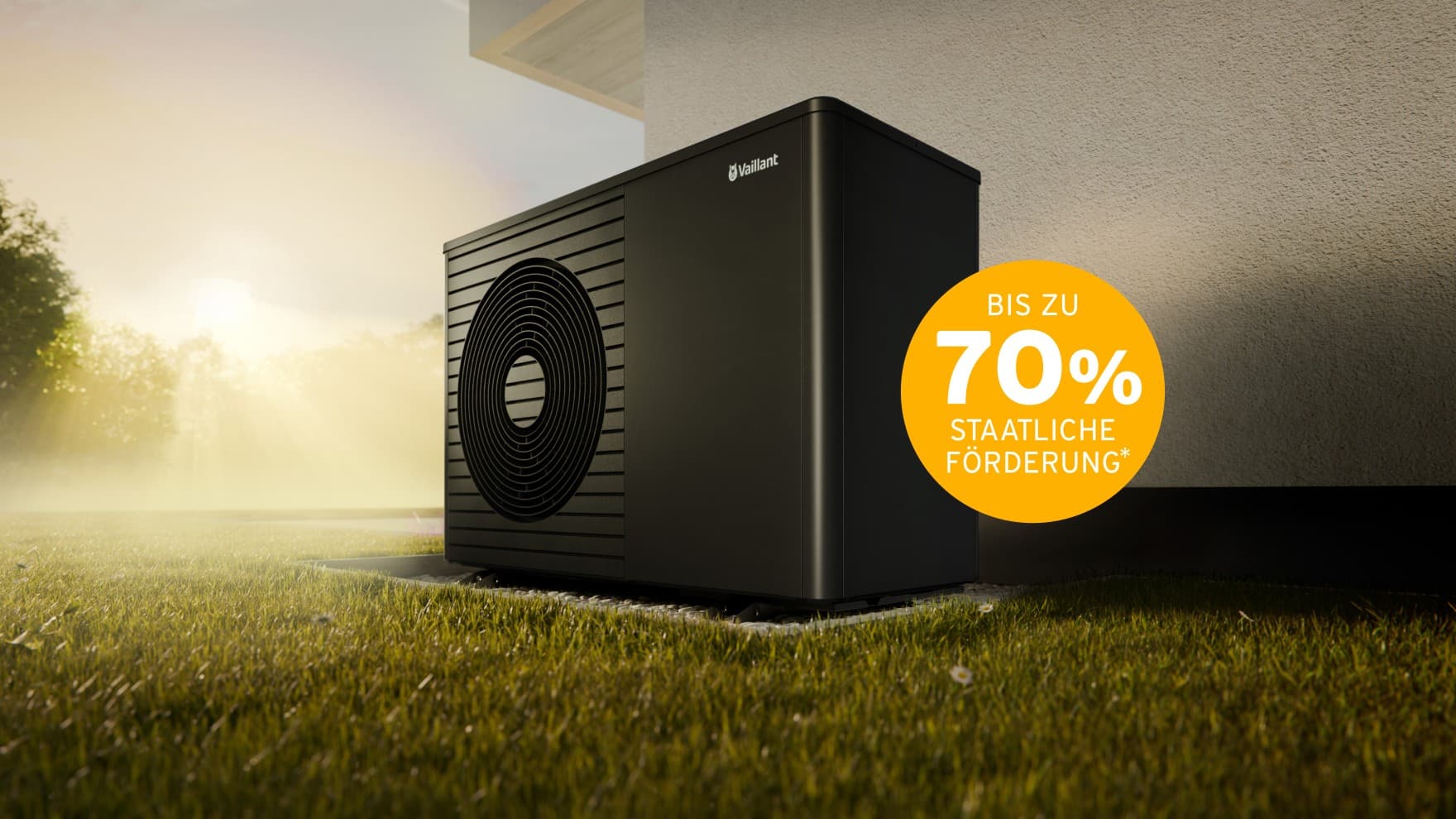 Die Vaillant aroTHERM plus steht vor einer Hauswand. Im Hintergrund sieht man einen Sonnenuntergang und Bäume